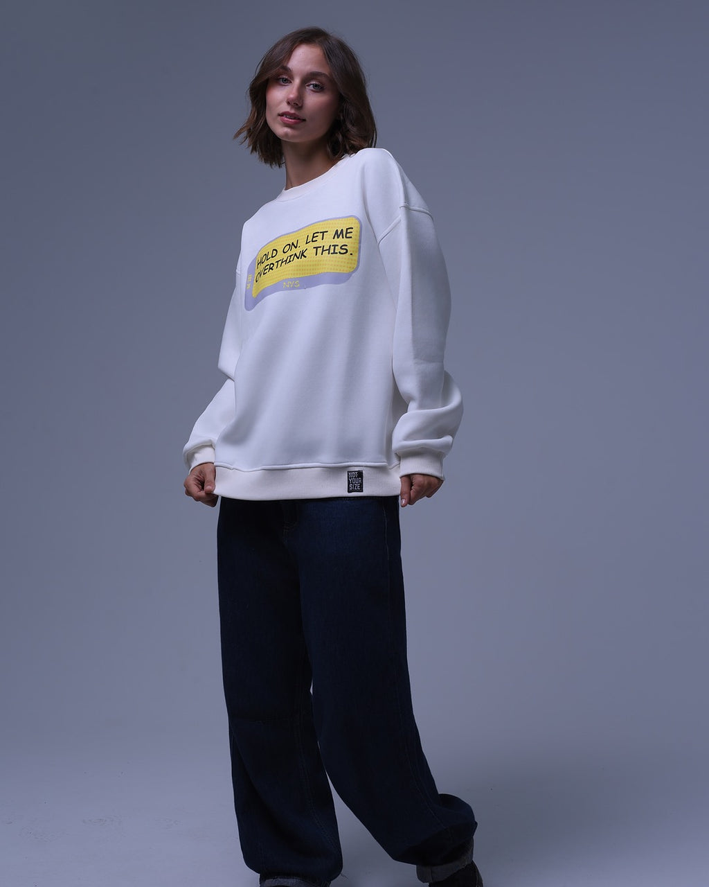 NotYourSize2025 white oversized crewneck sweatshirt with text print worn by model with black pants